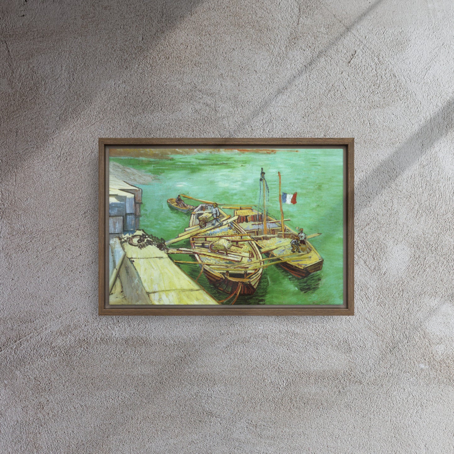 Van Gogh's 'Quay with Men Unloading Sand Barges' on a 12"x18" brown framed canvas print on a textured gray wall.