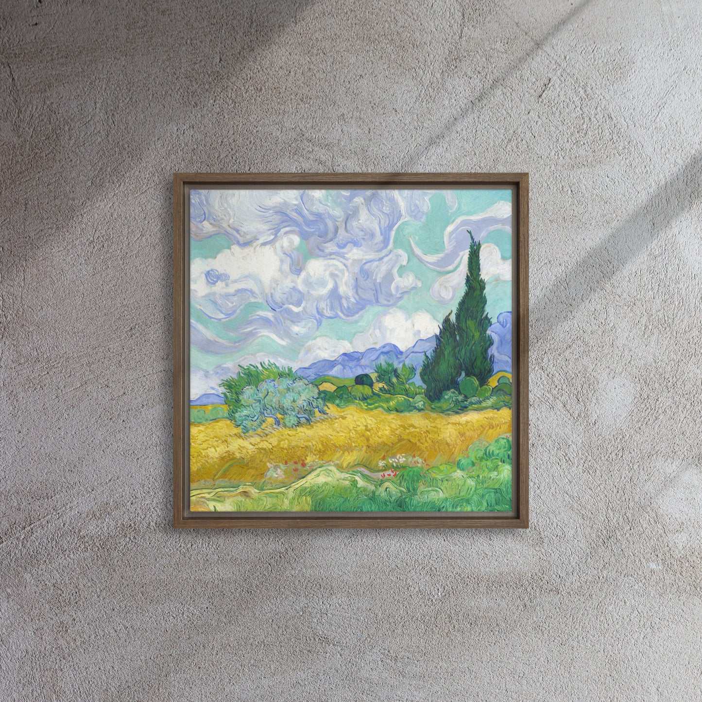 Van Gogh's 'Wheat Field with Cypresses' on a 16"x16" brown framed canvas print on a textured gray wall.