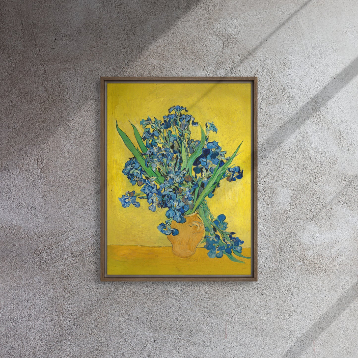 Van Gogh's 'Vase with Irises Against a Yellow Background' on a 18"x24" brown framed canvas print on a textured gray wall.