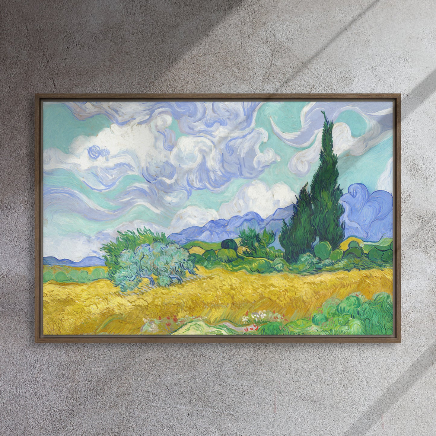 Van Gogh's 'Wheat Field with Cypresses' on a 24"x36" brown framed canvas print on a textured gray wall.