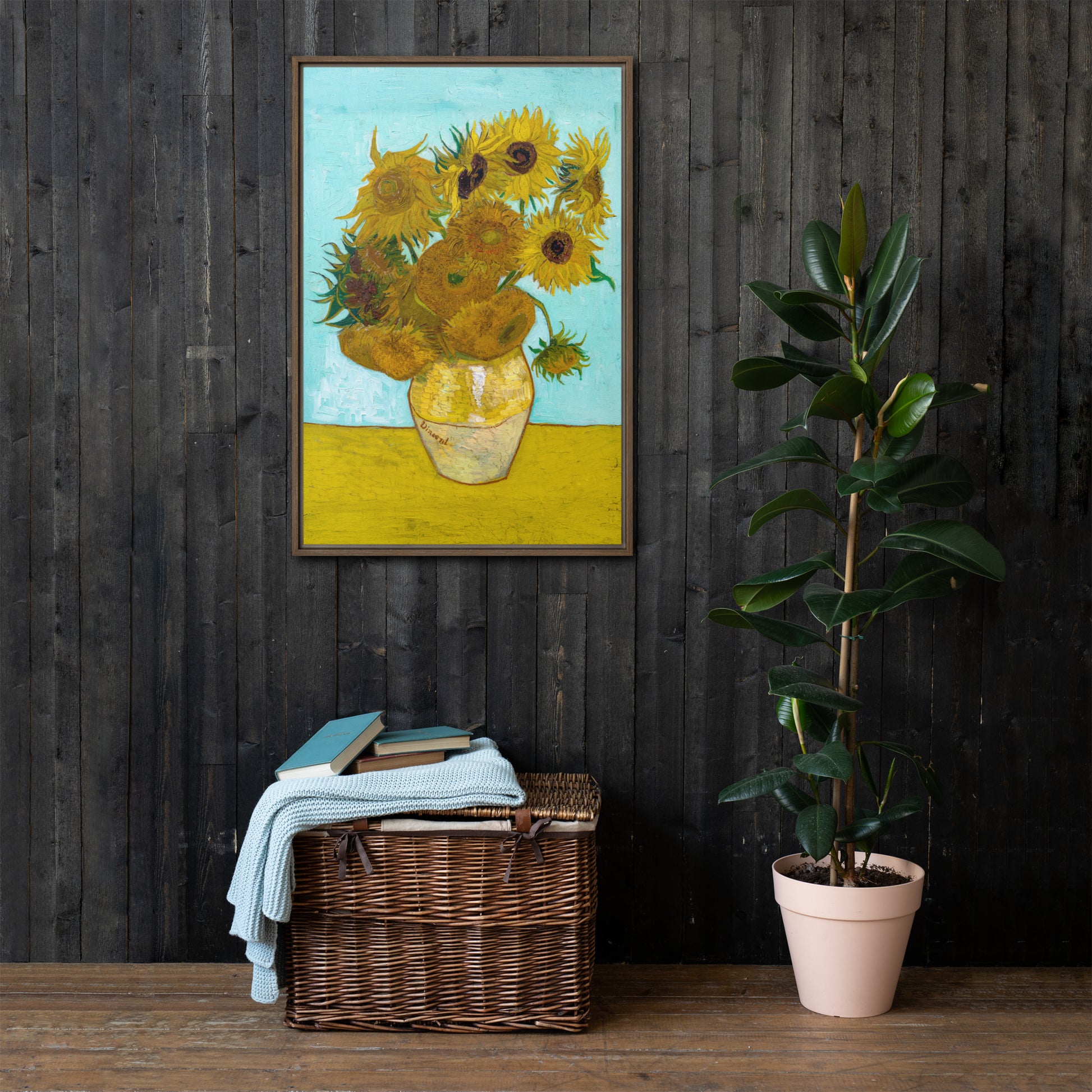 Van Gogh's 'Vase with Twelve Sunflowers' on a 24"x36" brown framed canvas print on a dark wooden wall with a wicker bin and plant below.