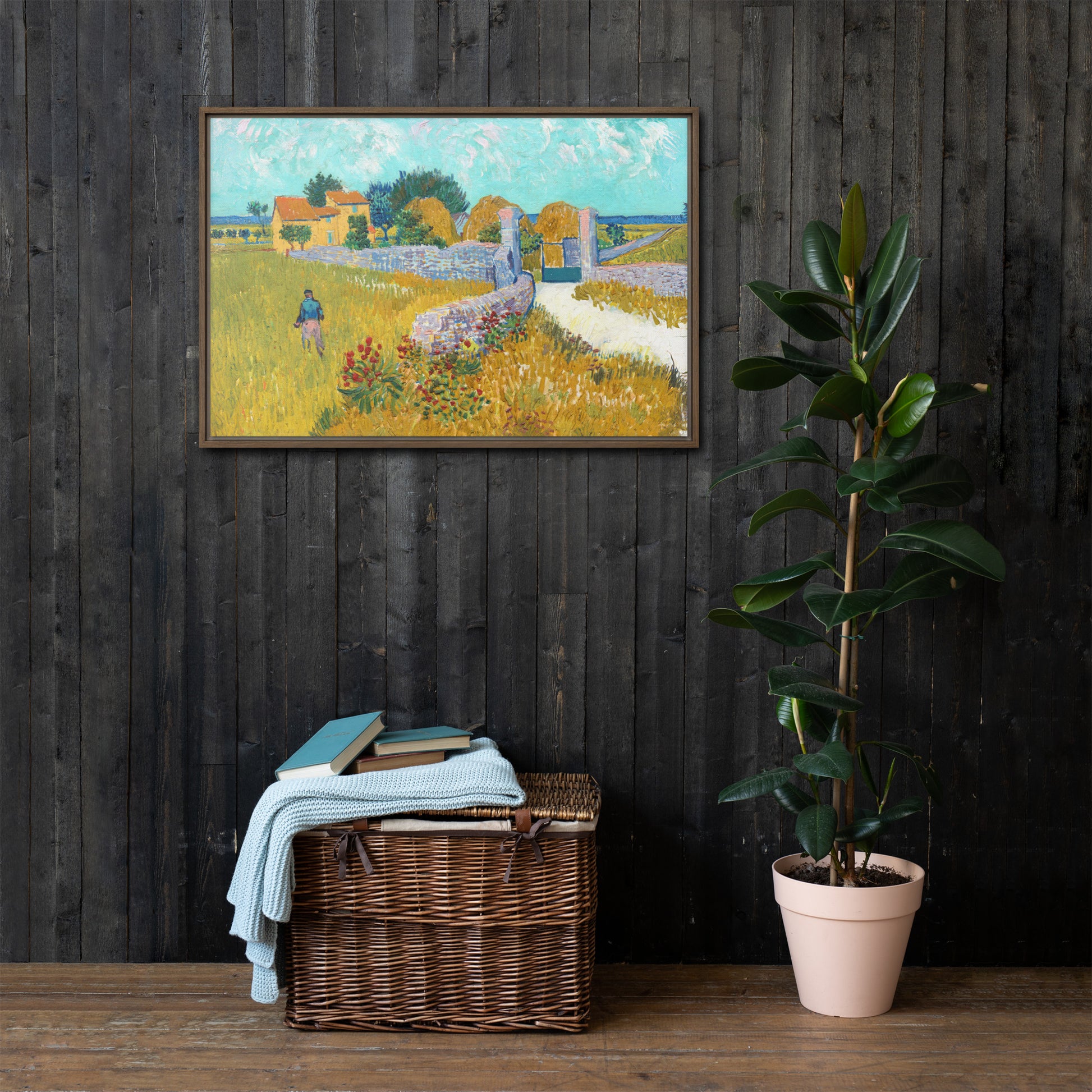 Van Gogh's 'Farmhouse in Provence' on a 24"x36" brown framed canvas print on a dark wooden wall with a wicker bin and plant below.