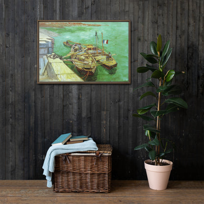 Van Gogh's 'Quay with Men Unloading Sand Barges' on a 24"x36" brown framed canvas print on a dark wooden wall with a wicker bin and plant below.
