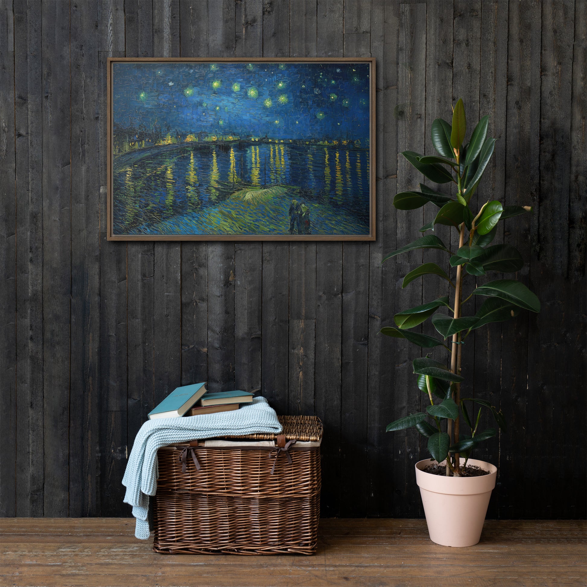 Van Gogh's 'Starry Night Over the Rhone' on a 24"x36" brown framed canvas print on a dark wooden wall with a wicker bin and plant below.