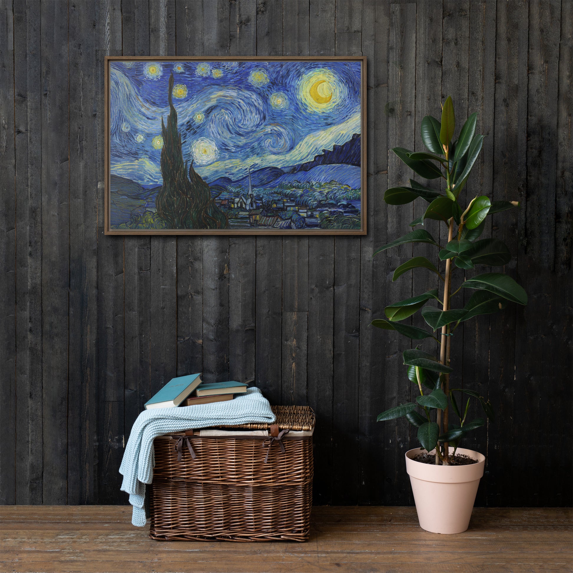 Van Gogh's 'Starry Night' on a 24"x36" brown framed canvas print on a dark wooden wall with a wicker bin and plant below.
