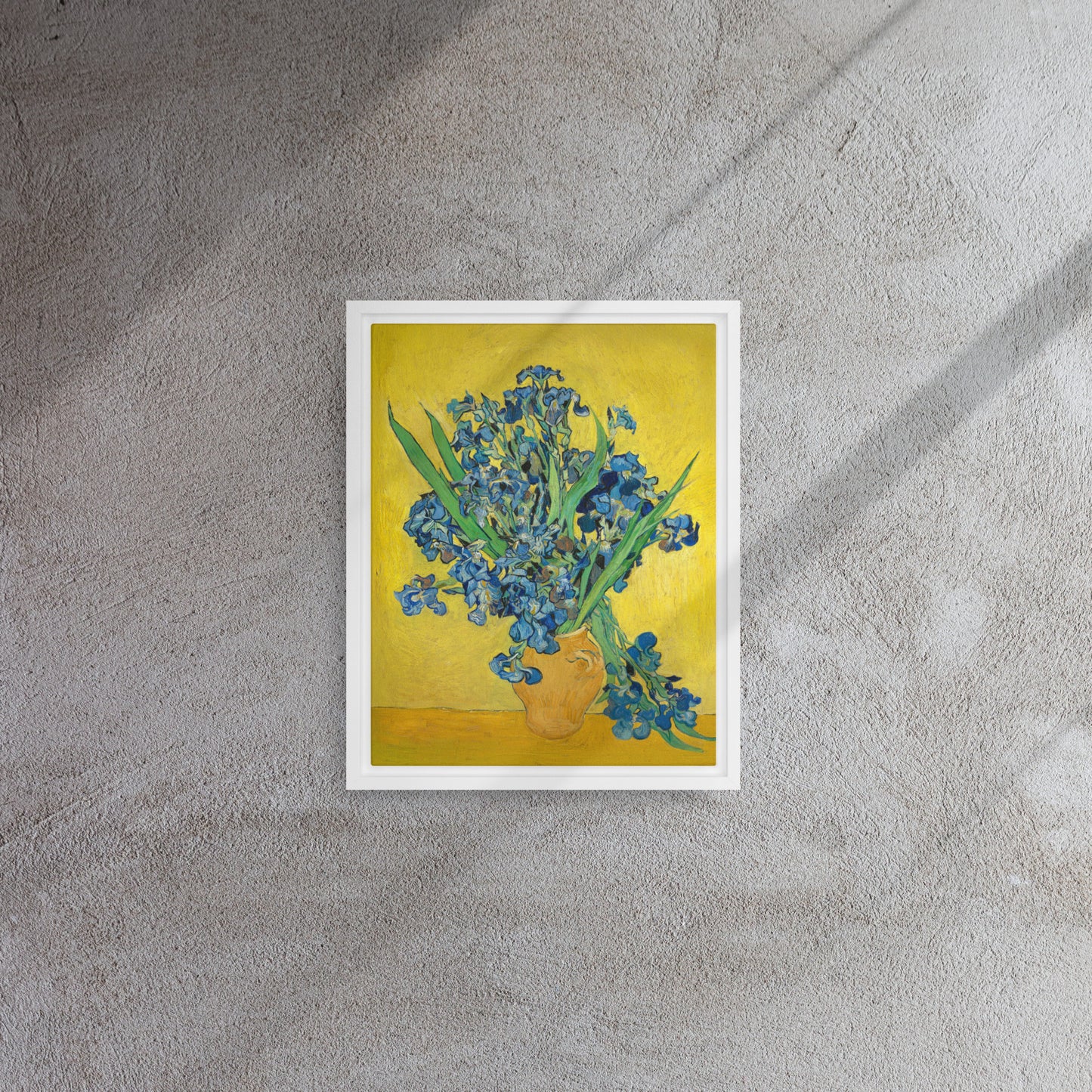 Van Gogh's 'Vase with Irises Against a Yellow Background' on a 11"x14" white framed canvas print on a textured gray wall.
