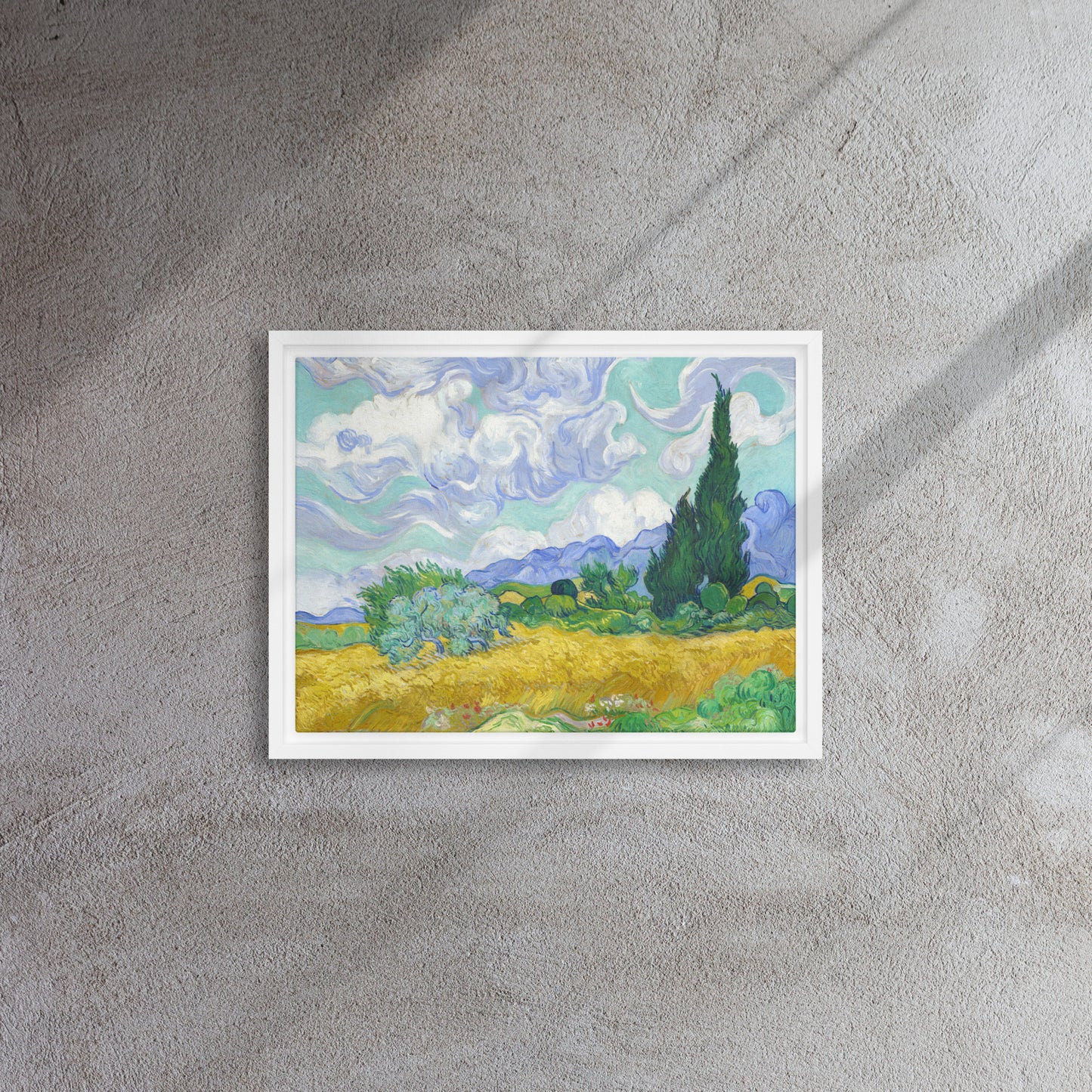 Van Gogh's 'Wheat Field with Cypresses' on a 12"x16" white framed canvas print on a textured gray wall.