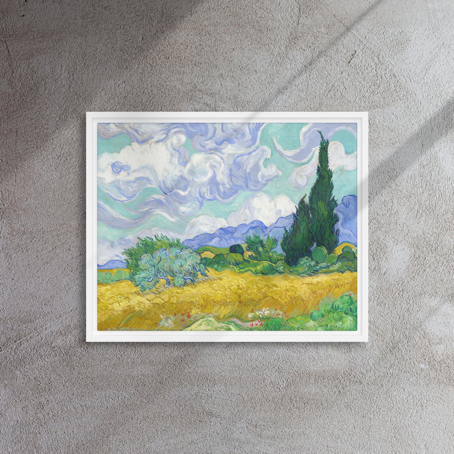Van Gogh's 'Wheat Field with Cypresses' on a 16"x20" white framed canvas print on a textured gray wall.