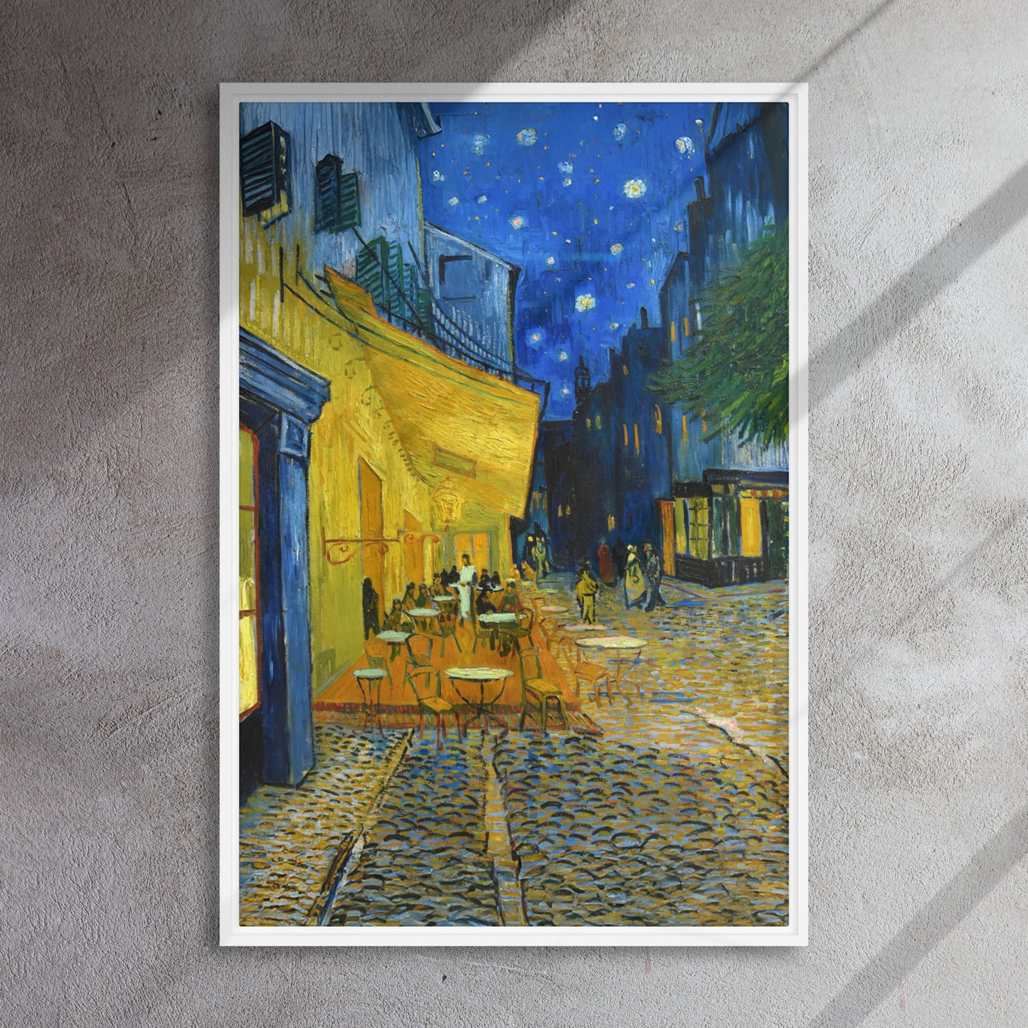 Van Gogh's 'Café Terrace at Night' on a 24"x36" white framed canvas print on a textured gray wall.