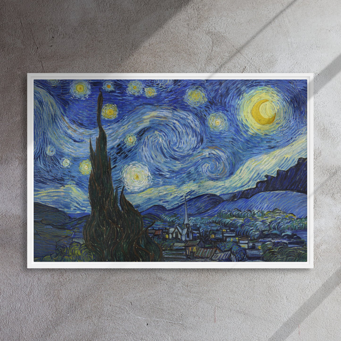 Van Gogh's 'Starry Night' on a 24"x36" white framed canvas print on a textured gray wall.