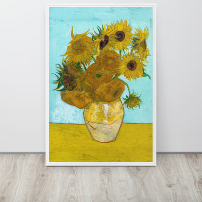 Van Gogh's 'Vase with Twelve Sunflowers' on a 24"x36" white framed canvas print sitting on a wooden floor leaning against a light gray wall.