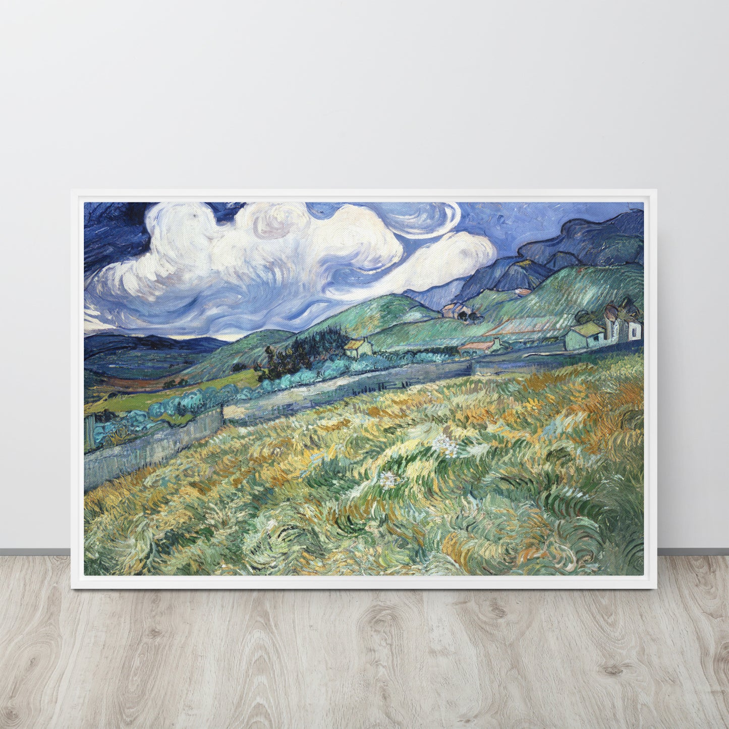 Van Gogh's 'Landscape from Saint-Rémy' on a 24"x36" white framed canvas print sitting on a wooden floor leaning against a light gray wall.